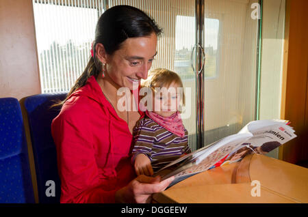 Joven madre con su hijo la lectura en un libreto interior tren ICE, Dresde, Sajonia, Alemania Foto de stock