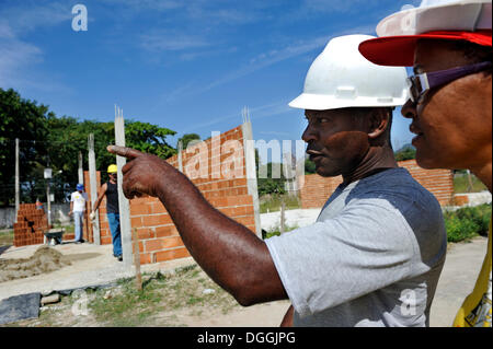 Supervisor de obras y el presidente de la 'Esperanca' cooperativa de vivienda de inspeccionar el sitio de construcción, cada familia Foto de stock