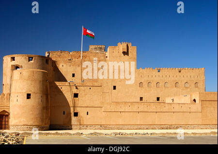Fort Jabrin marcados con bandera nacional de Omán, hechas de arcilla histórico Fort en la región Dhakiliya, Sultanato de Omán Foto de stock