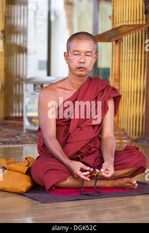 Un monje meditando en la postura del loto en frente de Budas de oro Fotografía de stock Alamy