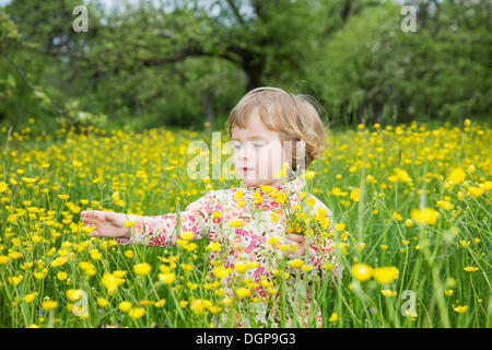 Niña jugando en un prado de flores