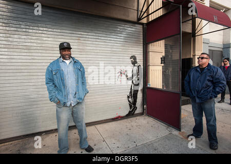 Nueva York, NY, EE.UU . 24 Oct, 2013. Los entusiastas del arte de la calle Grey a Larry Flynt Hustler's Club en el Hells Kitchen barrio de Nueva York el jueves, 24 de octubre de 2013 para ver "esperando en vano" la vigésimo cuarta entrega de Banksy graffiti del art. El estarcida ilustraciones está en la puerta de roll-up en la entrada al club de caballeros, que se ha publicado fuera de guardias de seguridad para proteger su nueva obra maestra. El escurridizo artista callejero es la creación de obras en los alrededores de la ciudad cada día durante el mes de octubre llamado "Mejor que". (© Richard B. Levine) Credit: Richard Levine/Alamy Live N Foto de stock