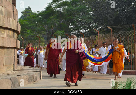 Y monjes y monjas budistas tibetano Rimpoché caminando alrededor del histórico sitio de peregrinación Budista Stupa Dhamekh Foto de stock