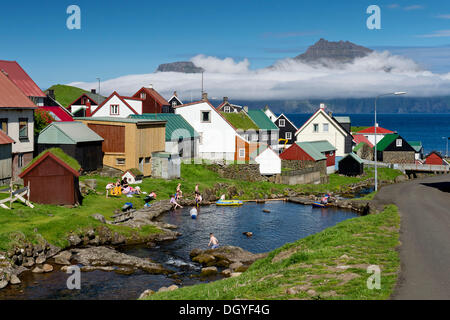 Aldea con típicas casas coloridas, niños jugando en un arroyo en la parte delantera, Gjogv, Eysturoy, Islas Feroe, Dinamarca