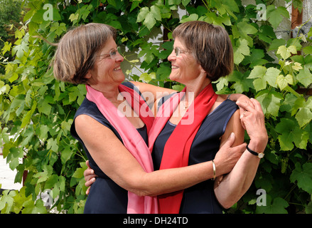 La lujuria de hermanas gemelas, vestidos igual en bufandas rojas, Retrato Foto de stock
