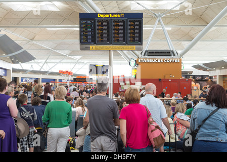 Gente esperando en la atestada sala de salidas del aeropuerto de Stansted, Inglaterra, Reino Unido. Foto de stock