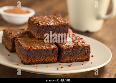 Bizcocho de chocolate recién horneadas piezas sobre una placa con la copa en la parte de atrás (enfoque selectivo) Foto de stock