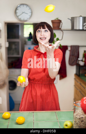 Mujer joven en cocina malabarismo limones