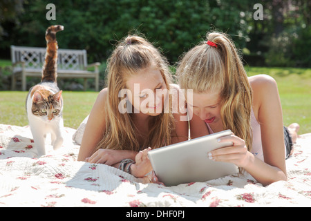 Dos chicas adolescentes en manta para picnic mirando tableta digital