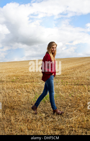 Retrato de mujer joven caminando en campo cosechado