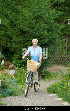 Mujer senior de equitación en el parque de bicicletas