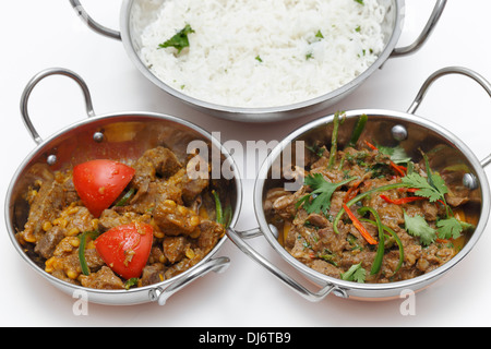 Un plato de curry de cordero aderezado con hojas de cilantro y chiles, junto a un tazón de Lahore-style Cordero al curry y algo de arroz Foto de stock