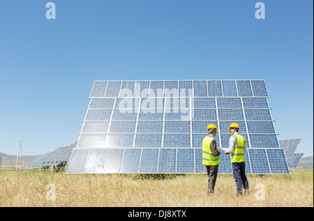 Trabajadoras, examinando el panel solar en paisaje rural Foto de stock