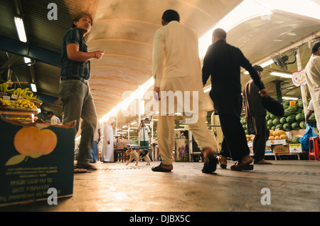 Hombres árabes caminando por uno de los pasillos en Deira, Mercado de frutas y vegetales durante el amanecer. Dubai, Emiratos Árabes Unidos. Foto de stock