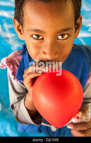 Rosivula, una alumna de 6 años de edad (en su uniforme) soplando un globo un turista (un yachtie) le había dado. Fulaga, Laus, Fiji Foto de stock