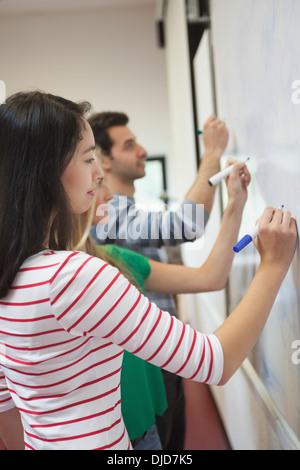 Los estudiantes escrito en la pizarra junto en clase Foto de stock