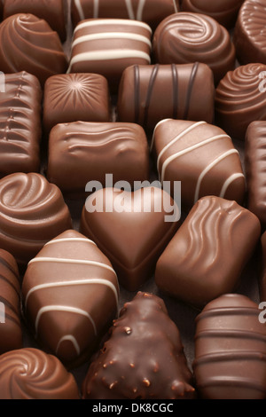 Un corazón de chocolate rodeado de surtido de chocolates de leche en una caja Foto de stock