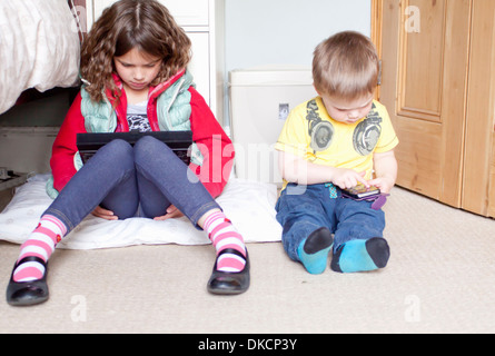 Los niños con digital tablet y teléfono móvil
