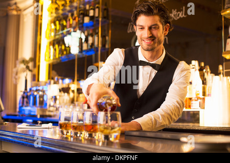 Bien vestida barman vertiendo en bourbon bar de lujo Foto de stock