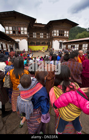 Bhután, Thangbi Mani Lhakang Tsechu Festival público viendo bailar en el patio Foto de stock