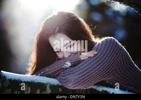 Mujer joven recostado sobre el tronco de un árbol en la nieve Foto de stock