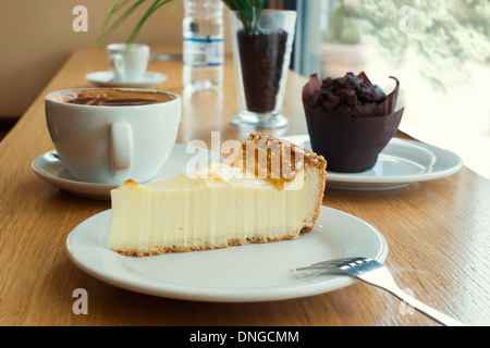 La tarta de queso, magdalenas, café y agua mineral en una tabla. Foto de stock