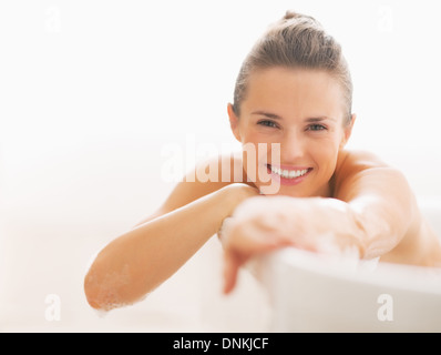 Sonriente joven mujer sentada en la bañera. Foto de stock