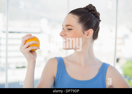 mujer morena en ropa deportiva naranja usando una hamaca azul aero