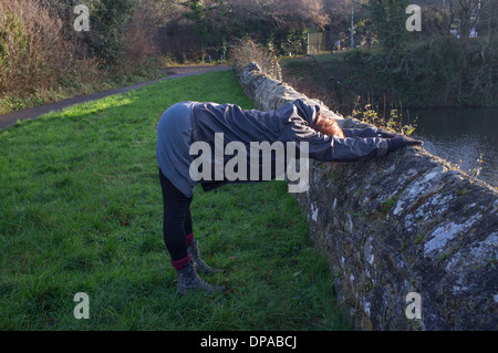 Una mujer que hace estirar la espalda mientras sales a caminar Foto de stock