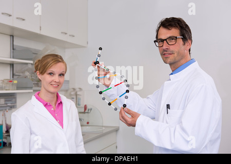 Retrato de dos científicos con modelo molecular de ADN
