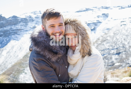 Pareja en chaquetas abrazando contra la montaña nevado Foto de stock