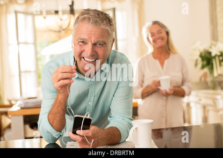 Hombre Senior escuchar el reproductor de mp3 en la cocina