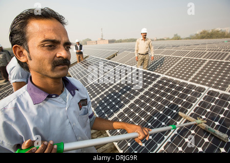 Trabajadores lavándose el polvo de los paneles solares en una estación de energía solar de 1 MW dirigidos por Tata power en el techo de una compañía eléctrica Foto de stock
