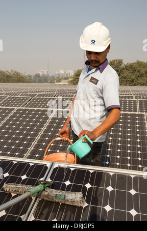 Trabajadores lavándose el polvo de los paneles solares en una estación de energía solar de 1 MW dirigidos por Tata power en el techo de una compañía eléctrica Foto de stock