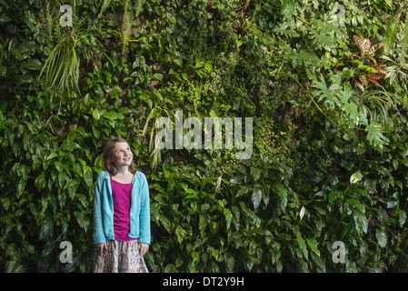 Ciudad en la primavera de un estilo de vida urbano una joven de pie frente a una pared cubierta de helechos y plantas trepadoras