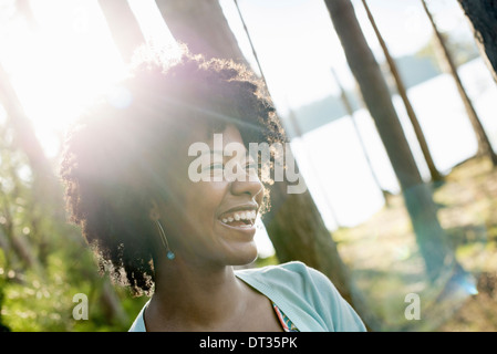 Una mujer joven con cabello negro rizado en la sombra de los árboles por una orilla del lago