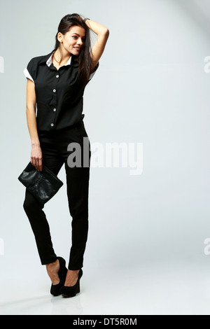 Feliz joven mujer ropa formal en negro sobre fondo gris permanente  Fotografía de stock - Alamy