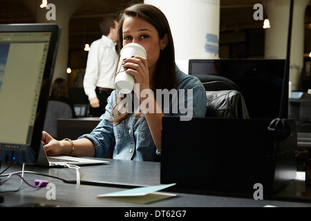 Mujer joven beber café en la oficina