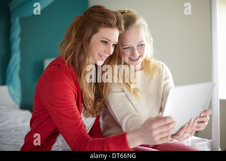 Dos chicas adolescentes mirando tableta digital en el dormitorio