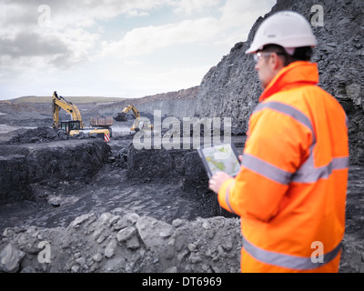 Miner comprueba planes sobre la tableta digital en la mina de carbón superficial