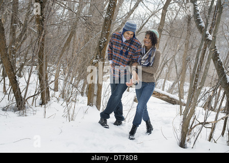 Paisaje invernal con nieve en el suelo. Una pareja del brazo caminando a través del bosque.