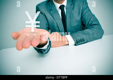 Un hombre de negocios sentado en un escritorio mostrando un yuan chino o japonés yen en su mano Foto de stock