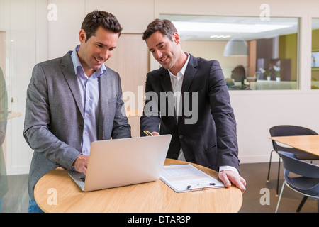 Dos empresarios informales que trabajan juntos en la oficina moderna con portátil