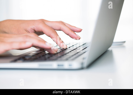 Cerca en manos de mujer escribiendo en el teclado portátil, equipo de oficina, el escritorio Foto de stock