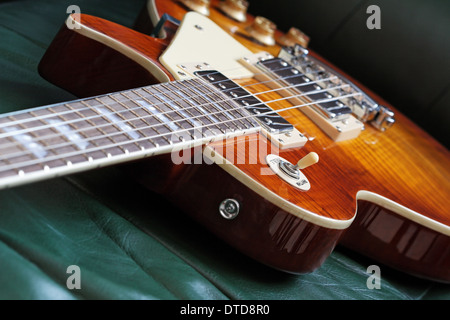 Elegante forma LP guitarra eléctrica, arce rojo sobre un fondo de cuero superior. DOF superficial. Foto de stock