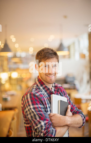 Hombre sujetando libros en cafe