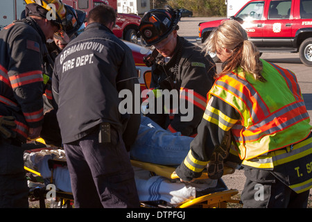 Los técnicos médicos de urgencias técnicos sanitarios y bomberos, ayudar a un paciente en una camilla Foto de stock