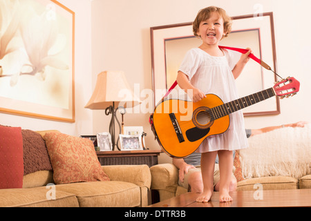 Chica hispana tocando la guitarra en el salón
