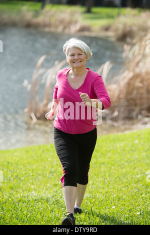 Senior mujer caucásica jogging en el parque Foto de stock