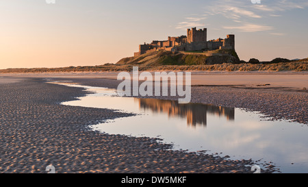 Bamburgh Castle y reflexión en Bamburgh Beach piscinas de marea, Northumberland, Inglaterra. La primavera (abril) de 2013.